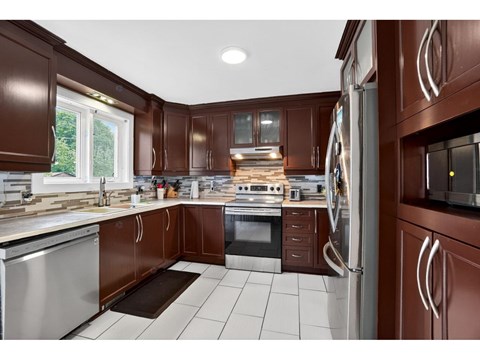 A kitchen with brown cabinets and a white tiled floor.