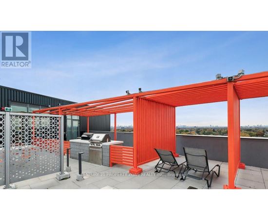 A balcony with a grill and chairs under an orange pergola.