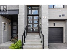 The image shows the front of a building with the number 107 and a glass door.
