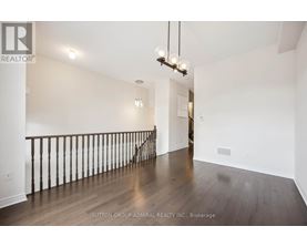 A spacious room with wooden floors and a staircase with a railing.
