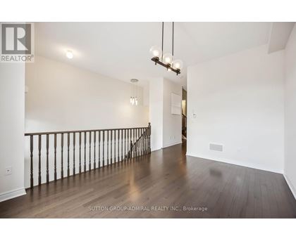 A spacious room with wooden floors and a staircase with a railing.