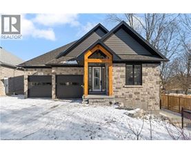 A house with a brown door and a stone facade is surrounded by snow.