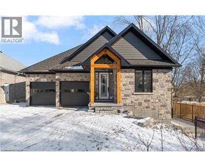 A house with a brown door and a stone facade is surrounded by snow.