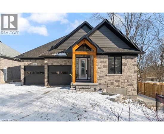 A house with a brown door and a stone facade is surrounded by snow.