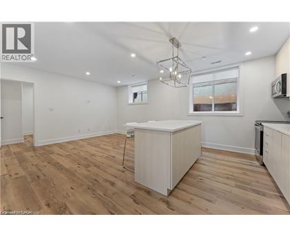 A well-lit kitchen with wooden floors and white cabinetry.