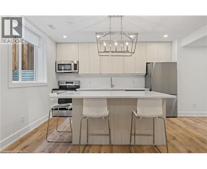 A modern kitchen with a bar stool and a microwave above the counter.