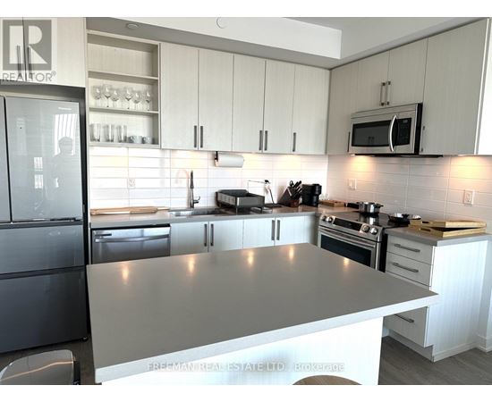 A modern kitchen with a black fridge and a stainless steel island.