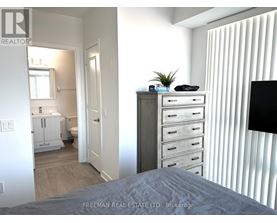 A bedroom with a bed, dresser, and a window with blinds.