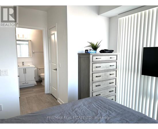 A bedroom with a bed, dresser, and a window with blinds.