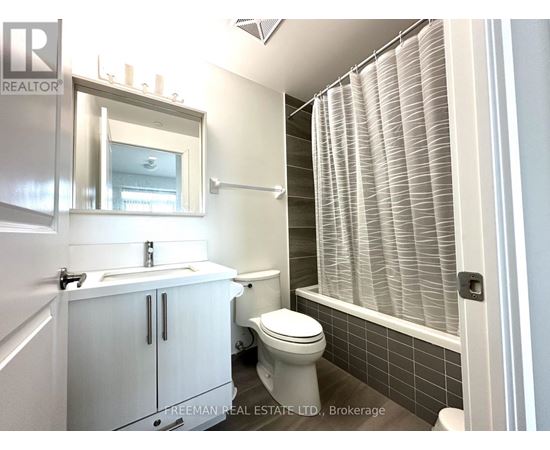 A white bathroom with a toilet, sink, and a window with blinds.