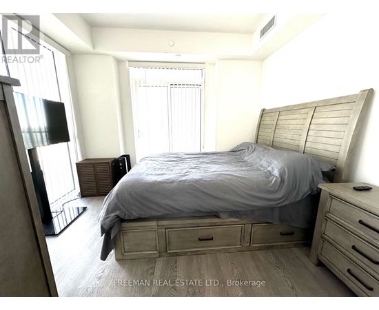 A bedroom with a bed, nightstand, and a television.