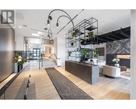 A modern interior space with a reception desk and hanging plants.