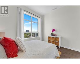 A bedroom with a large bed and a window overlooking a cityscape.