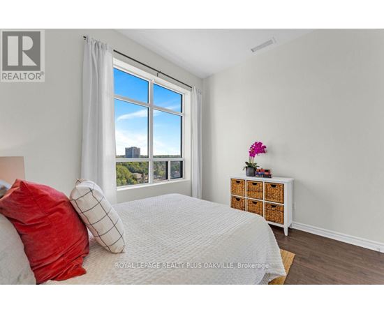 A bedroom with a large bed and a window overlooking a cityscape.
