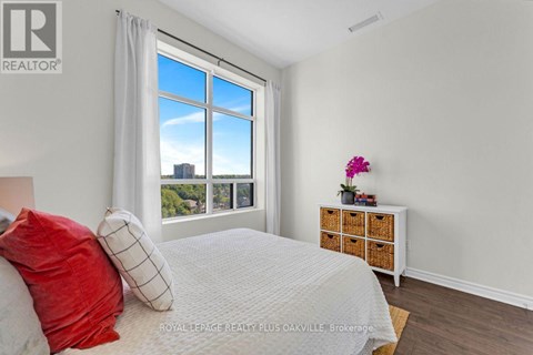 A bedroom with a large bed and a window overlooking a cityscape.