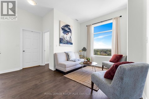 A well-lit living room with a couch, chair, and a painting on the wall.