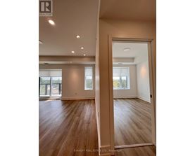 A spacious room with wooden flooring and a large window.