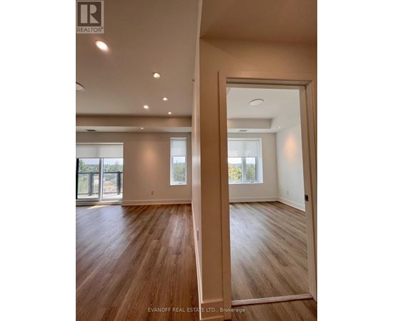 A spacious room with wooden flooring and a large window.