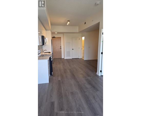 A spacious room with wooden flooring and white walls.