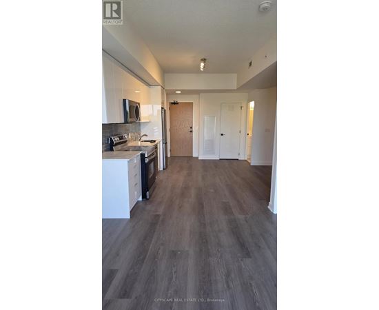 A kitchen with white cabinets and a wooden floor.