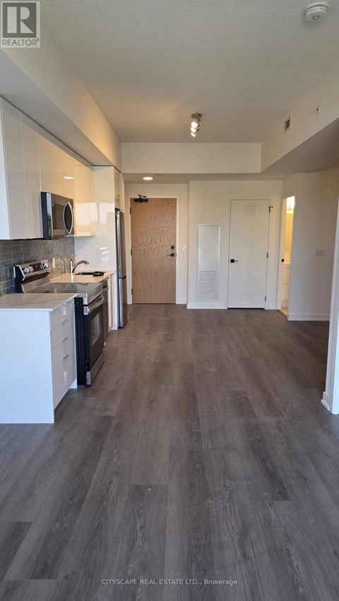 A kitchen with white cabinets and a wooden floor.