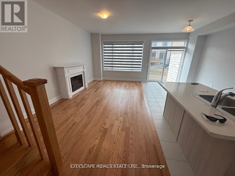A wooden floor leads to a kitchen area with a sink and a window.