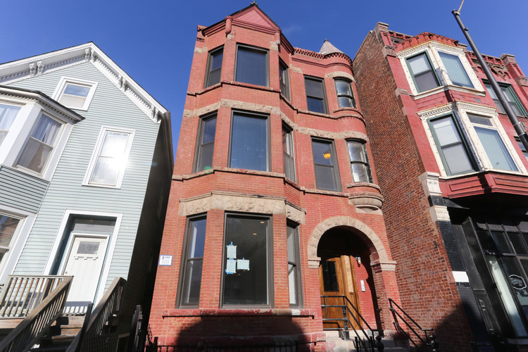 Three buildings with different facades stand next to each other.