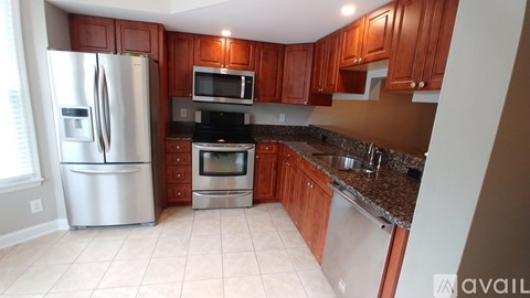 A kitchen with brown cabinets and a stainless steel refrigerator.