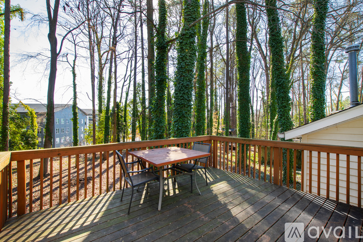 A wooden deck with a table and chairs surrounded by ivy covered trees.