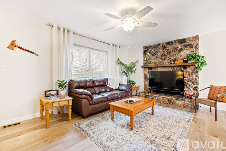 A living room with a brown leather couch, a wooden coffee table, and a stone fireplace.