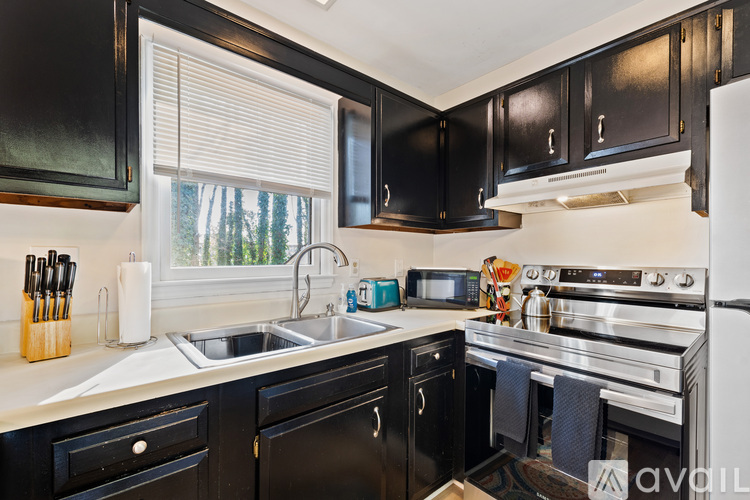 A kitchen with black cabinets and stainless steel appliances.