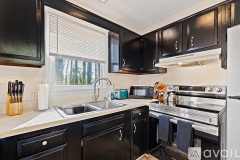 A kitchen with black cabinets and stainless steel appliances.