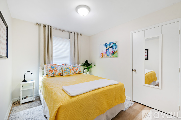 A bedroom with a yellow bedspread and a white bed.