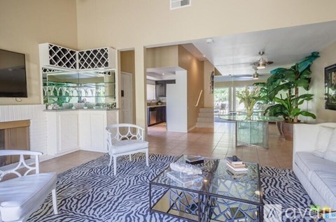 A living room with a zebra print rug and a glass coffee table.