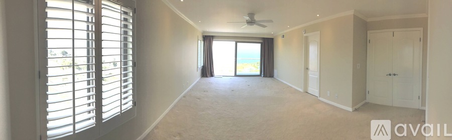 A spacious room with a sliding glass door leading to a balcony.