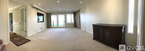 A spacious living room with a rug on the floor and a cabinet on the wall.