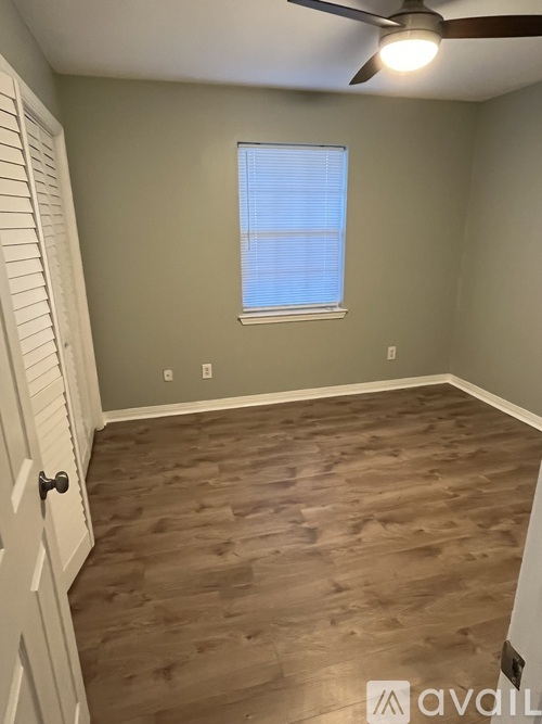 A room with a wooden floor and a window with blinds.