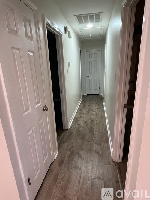A hallway with white doors and a wooden floor.