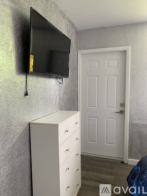 A white cabinet with a flat screen TV mounted above it.