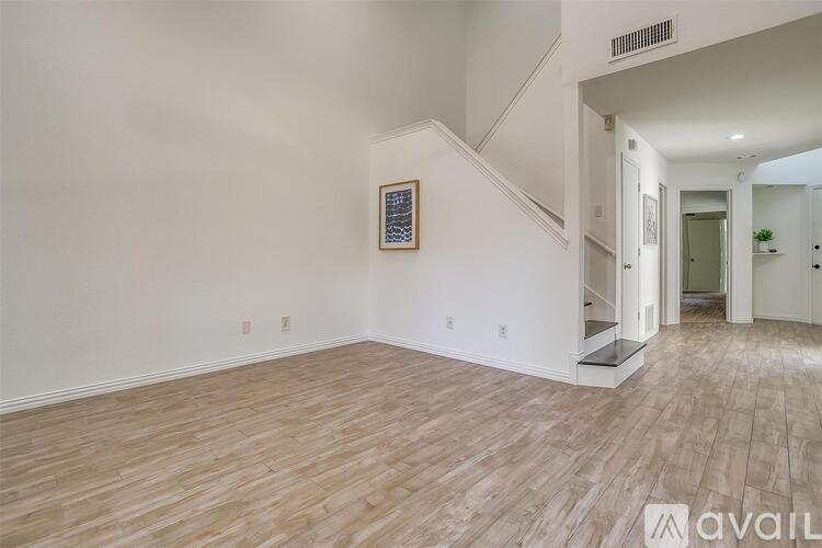 A room with wooden flooring and a staircase leading to another room.