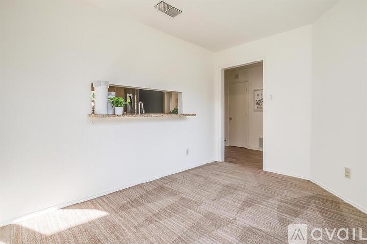 A room with a carpeted floor and a window with a view of a building outside.