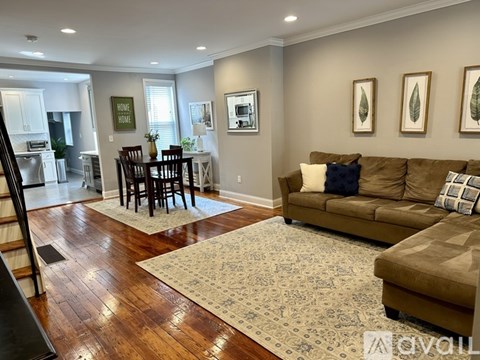 A living room with a brown couch and a rug.