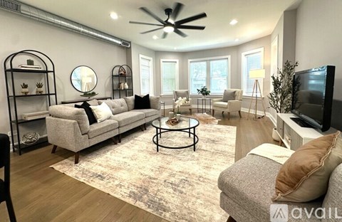 A living room with a grey couch, a black coffee table, and a television on the right side.