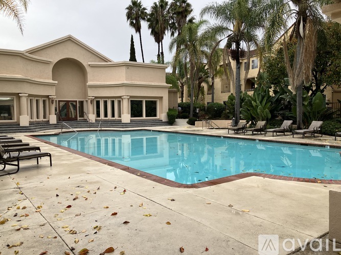 A pool surrounded by palm trees and a building.