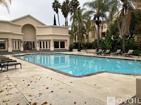 A pool surrounded by palm trees and a building.