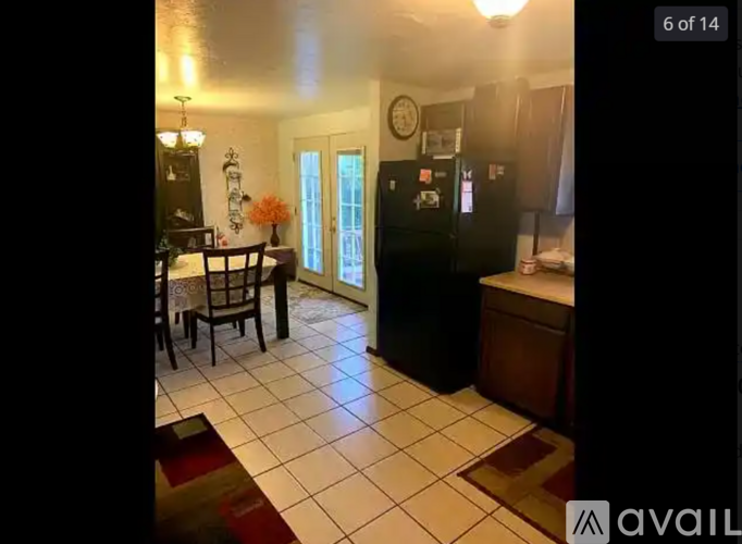 A kitchen with a black refrigerator and a dining table with chairs.