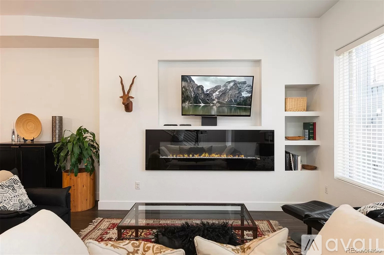 A living room with a fireplace and a television mounted above it.