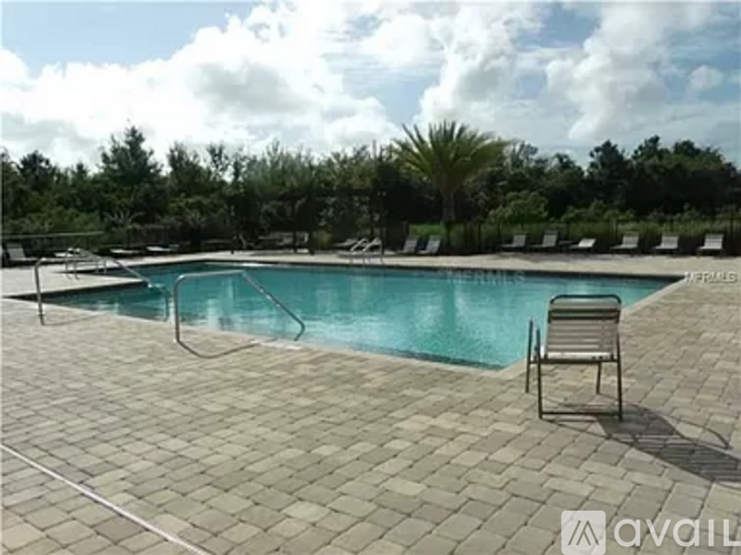 A pool surrounded by trees and chairs.