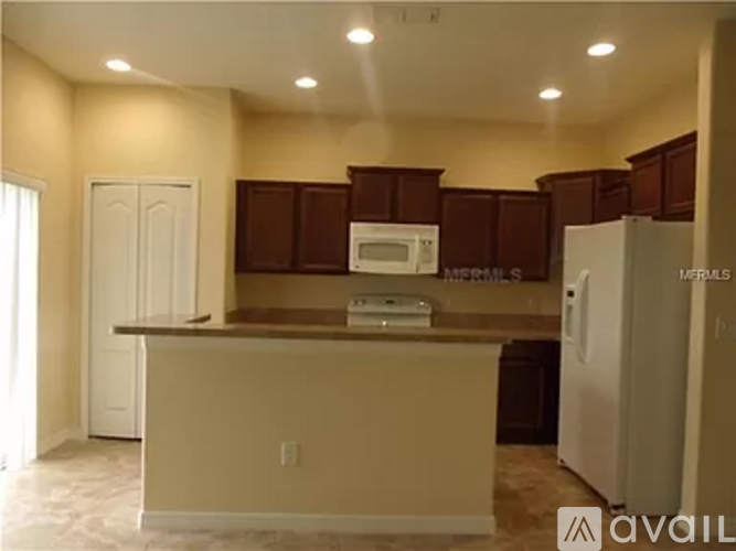 A kitchen with brown cabinets and a white refrigerator.