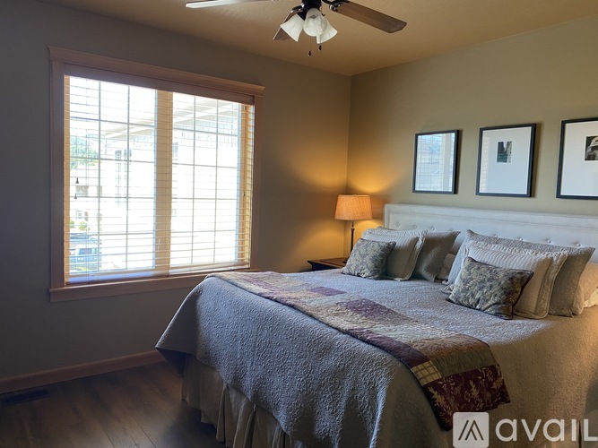 A bedroom with a bed, a ceiling fan, and a window with blinds.